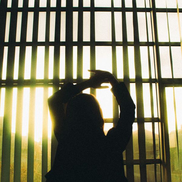 Silhouette of a woman in a dynamic yoga stretch against a subtle light source.