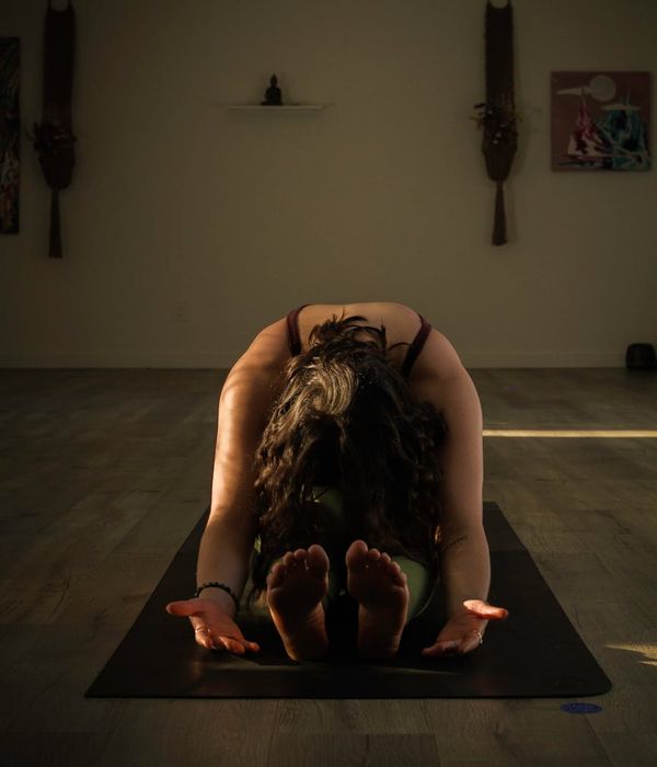 Woman performing a calm yoga pose in a dark, serene environment.